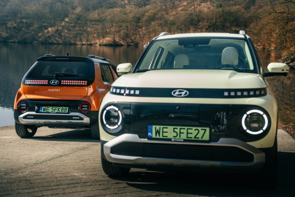 Hyundai INSTER nad jeziorem – z przodu wersja w kolorze kremowym, z tyłu pomarańczowy wariant z pikselowymi światłami.