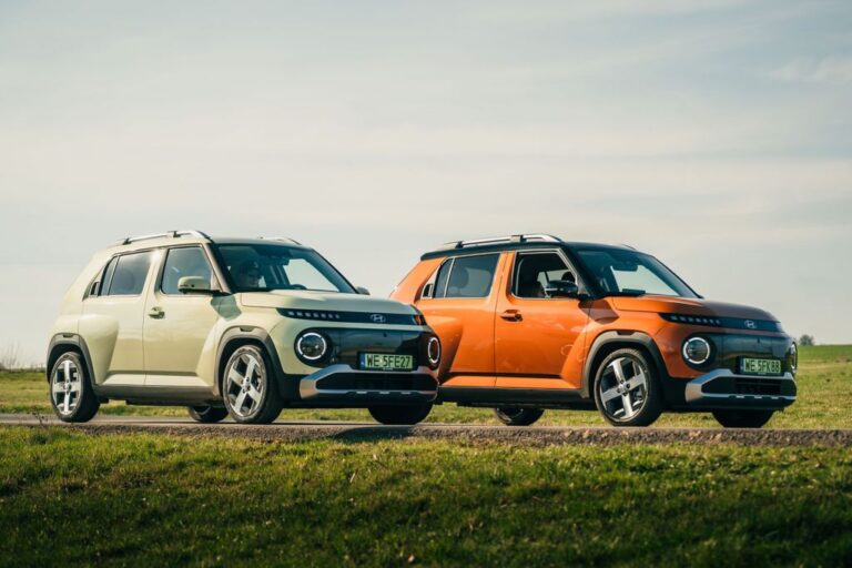 Hyundai INSTER w dwóch wersjach kolorystycznych – kremowej i pomarańczowej – zaparkowane na tle łąki i błękitnego nieba.