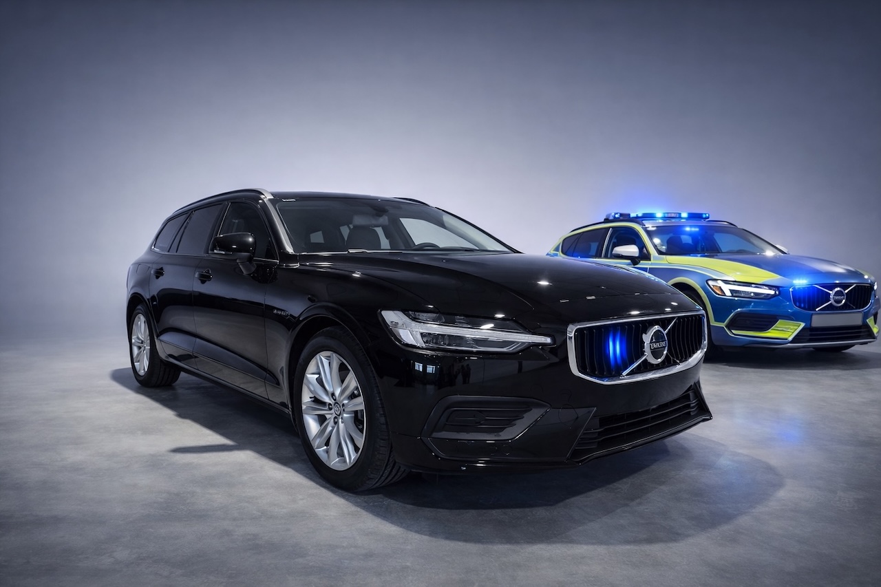 Czarny, nieoznakowany samochód Volvo V60 stojący obok wersji oznakowanej z niebieskimi światłami w grillu.