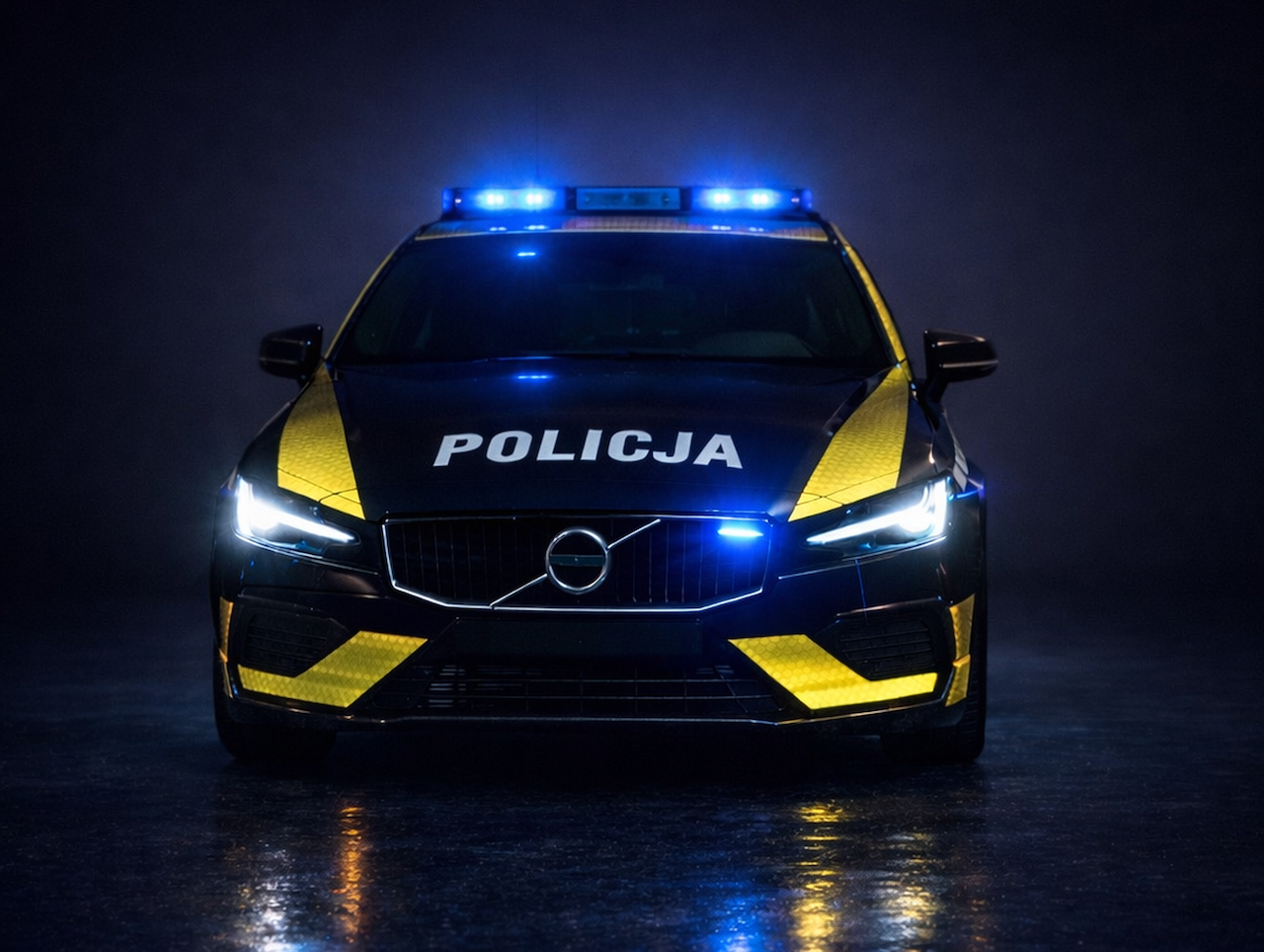 Front oznakowanego Volvo V60 z napisem „POLICJA” na masce i jaskrawymi, żółtymi pasami na zderzaku.