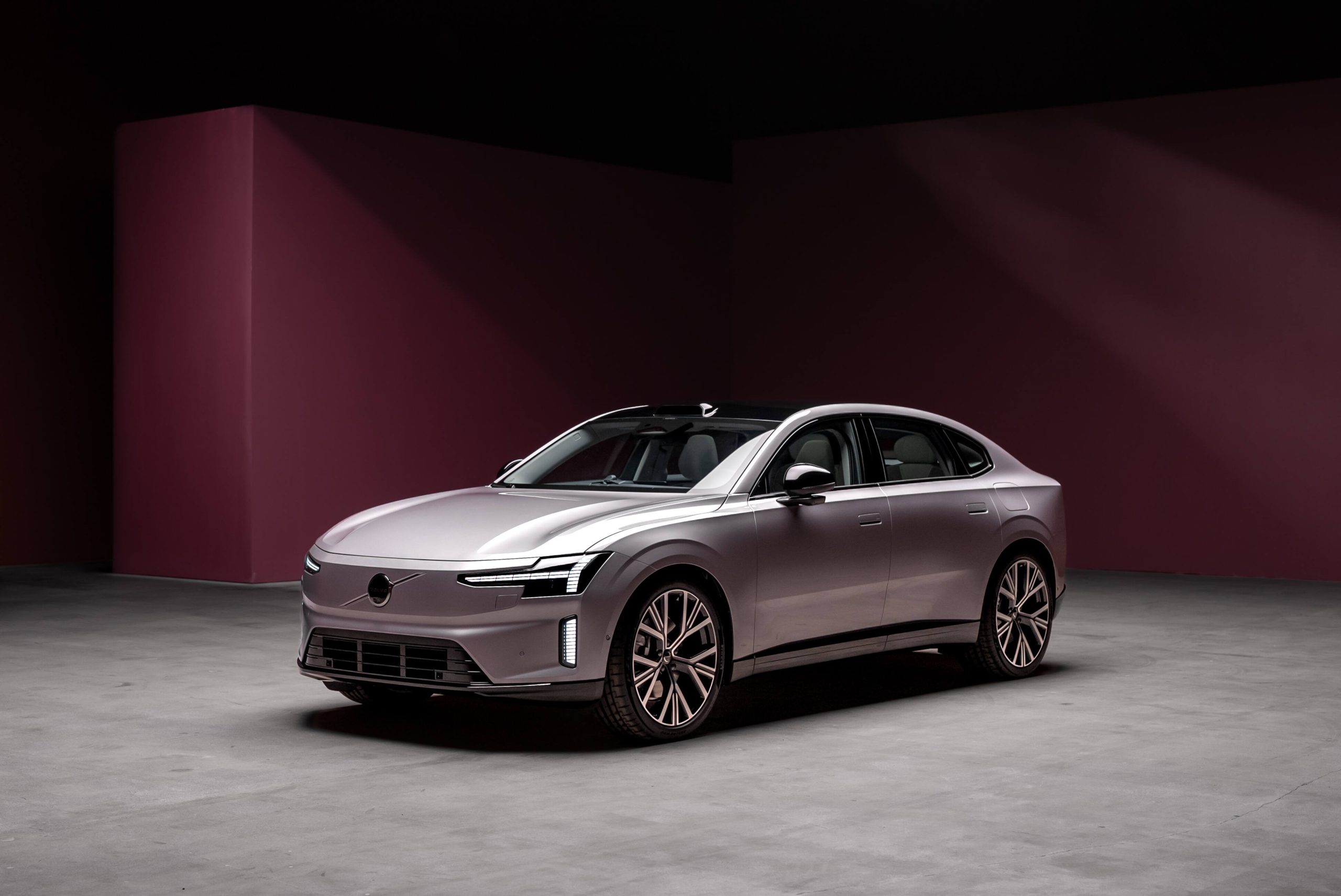 Profil luksusowej limuzyny Volvo ES90 zaparkowanej w studiu na tle purpurowej ściany.
