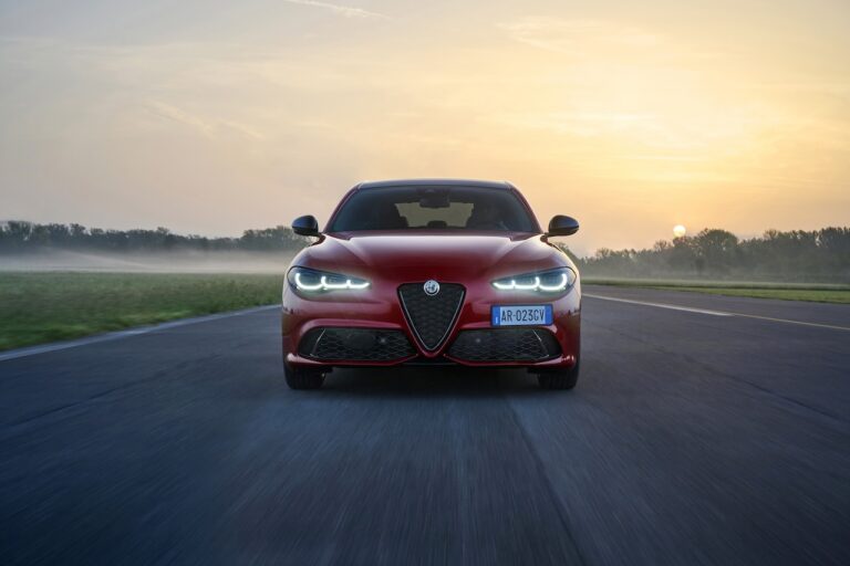 Czerwona Alfa Romeo Stelvio 2.2 Diesel Q4 na krętej, górskiej drodze – widok z przodu.