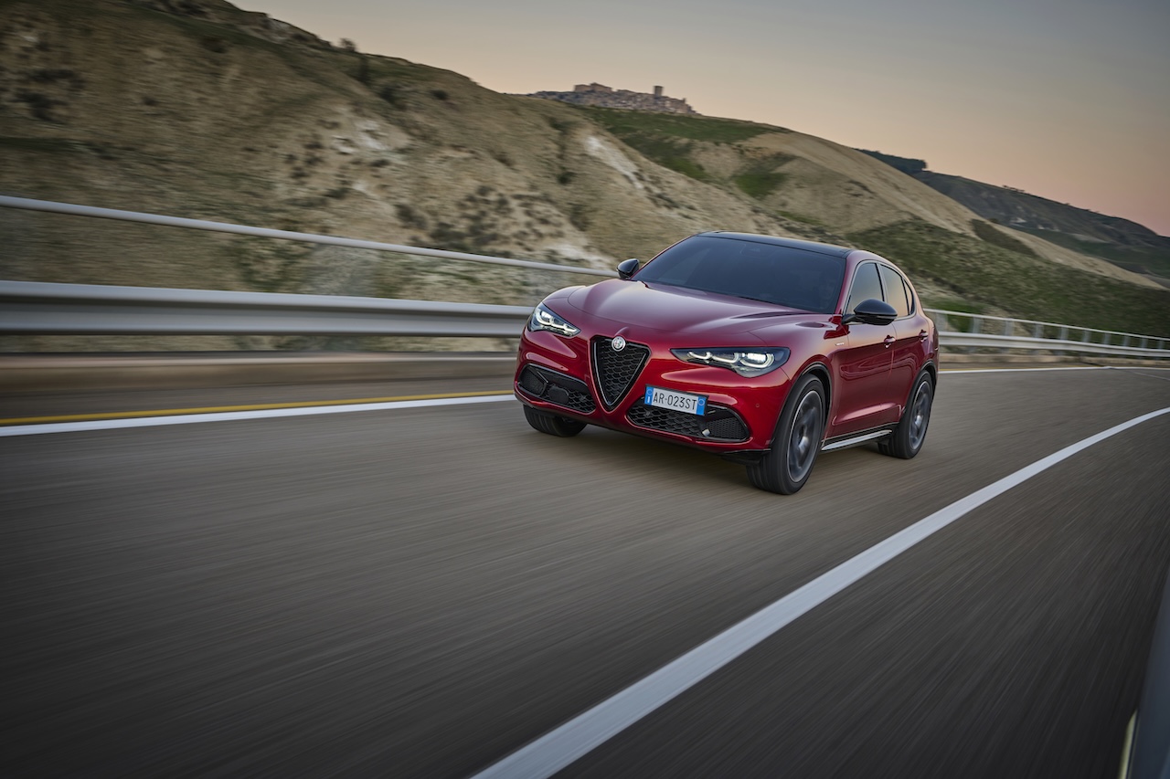 Czerwona Alfa Romeo Giulia 2.0 benzyna 280 KM w dynamicznej jeździe o zachodzie słońca.