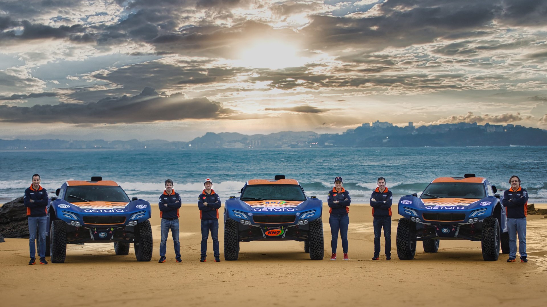 Załogi Astara TeamSamochody i rajdowcy na tle morza przy zachodzie słońca - na Rajd Dakar 2023
