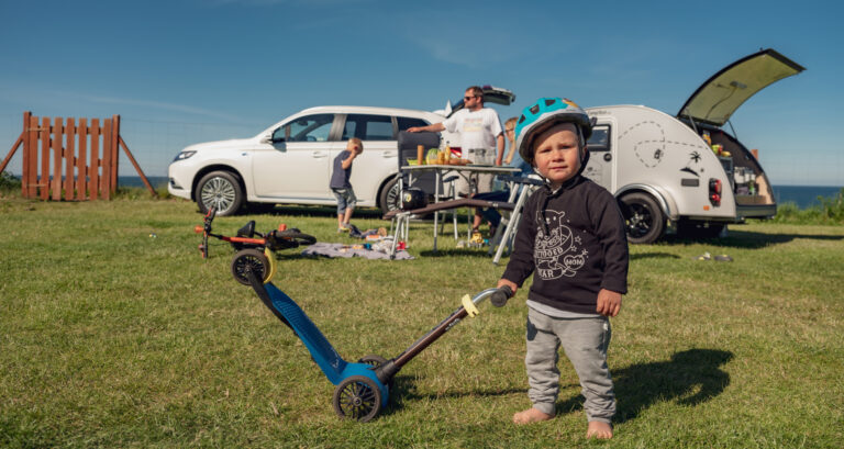 Samochód na wakacje, chłopiec z hulajnogą. Jak przygotować auto na wakacyjny wyjazd w długą trasę radzi serwis Mitsubishi