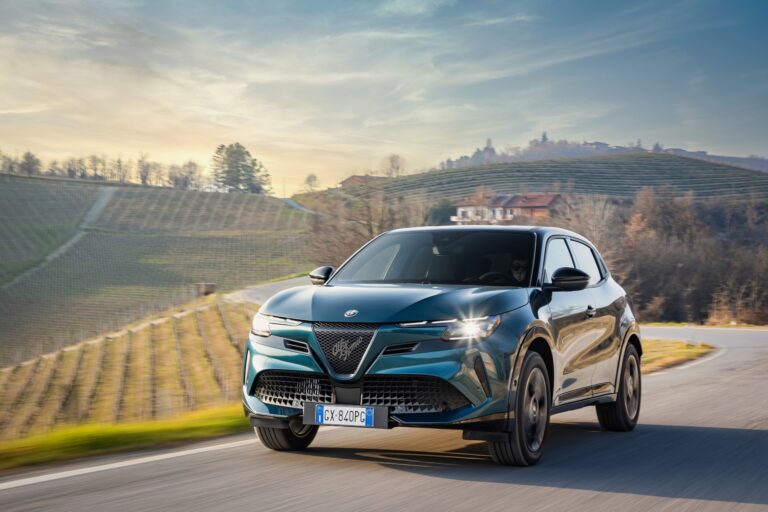 Alfa Romeo Junior Ibrida Q4 jadący po zakręcie w pagórkowatym krajobrazie