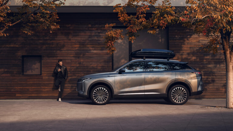 OMODA 9 Super Hybrid z boksem dachowym na tle drewnianej ściany