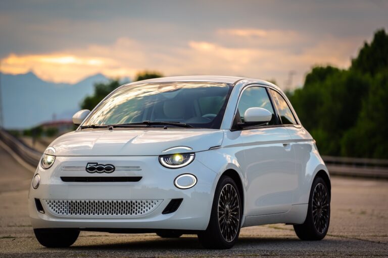 Nowy Fiat 500 Hybrid 2026 w kolorze białym – widok z przodu na tle zachodzącego słońca.