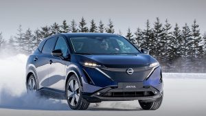 niebieski samochód w ruchu na śniegu, zima, choinki - zamówienia na Nissana Ariya