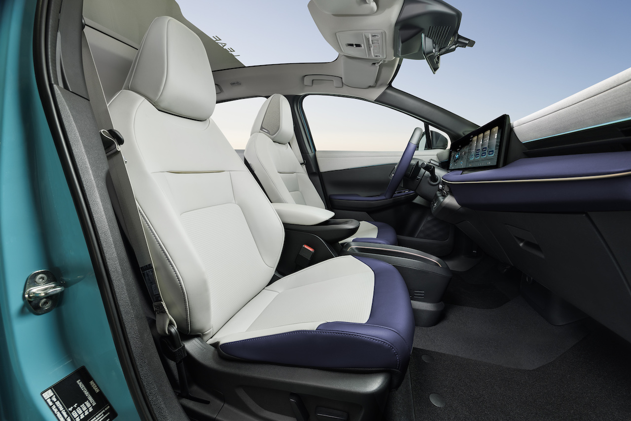 Widok na przednie fotele Nissana LEAF w kolorze biało-fioletowym oraz przeszklony dach panoramiczny z perspektywy pasażera.