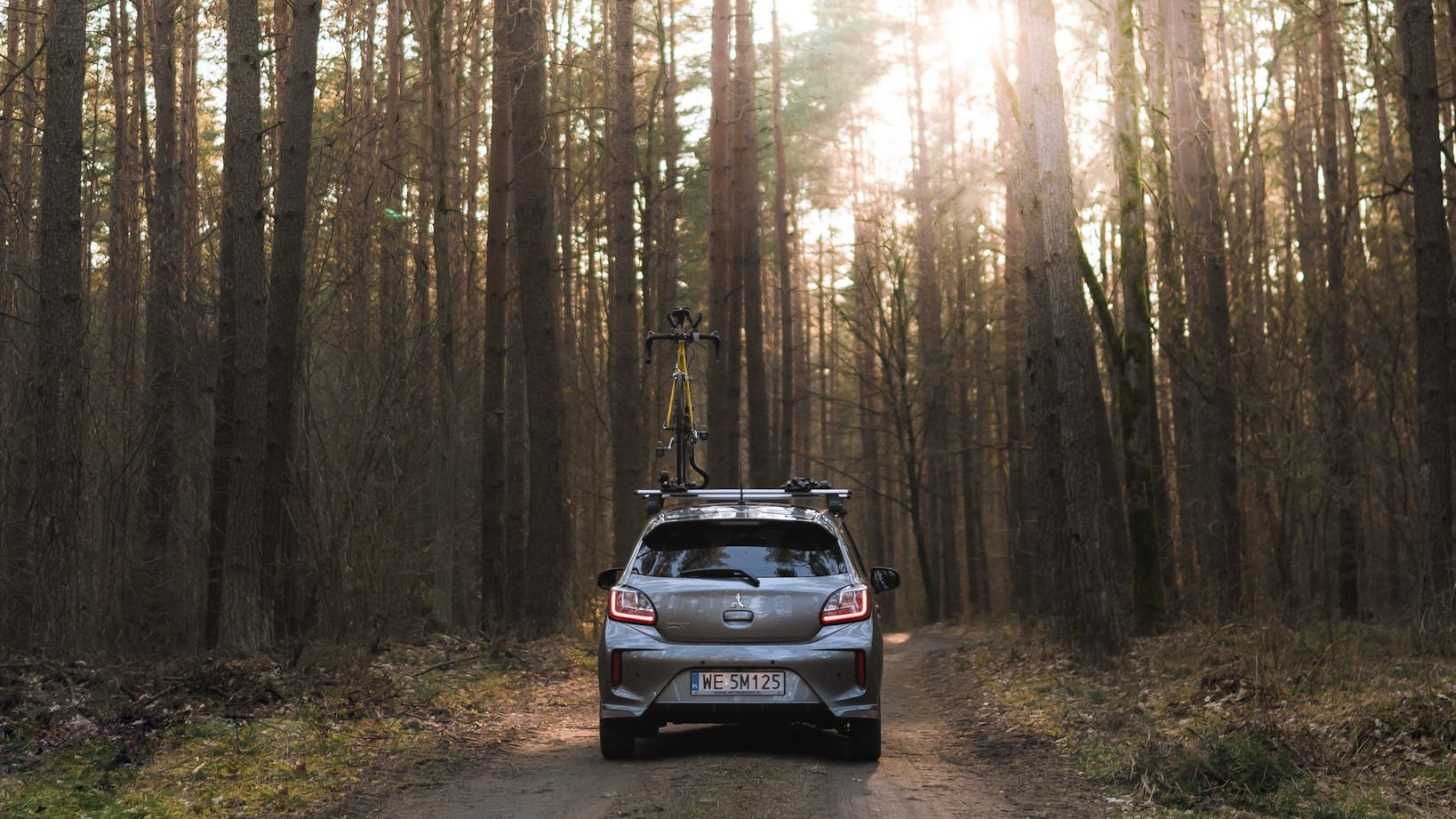 samochód z rowerem na leśnej drodze, promocja Mitsubishi, Space Star, wyprzedaż rocznika 2022, rabaty promocyjne kredyty i pakiety ubezpieczeń