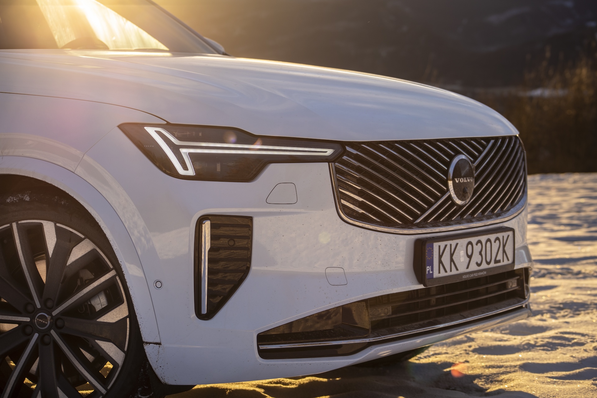Zbliżenie na przedni reflektor i grill Volvo XC90 po liftingu, sfotografowane o zachodzie słońca
