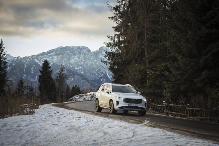 Volvo XC90 jadące po zaśnieżonej, górskiej drodze, w tle ośnieżone szczyty.