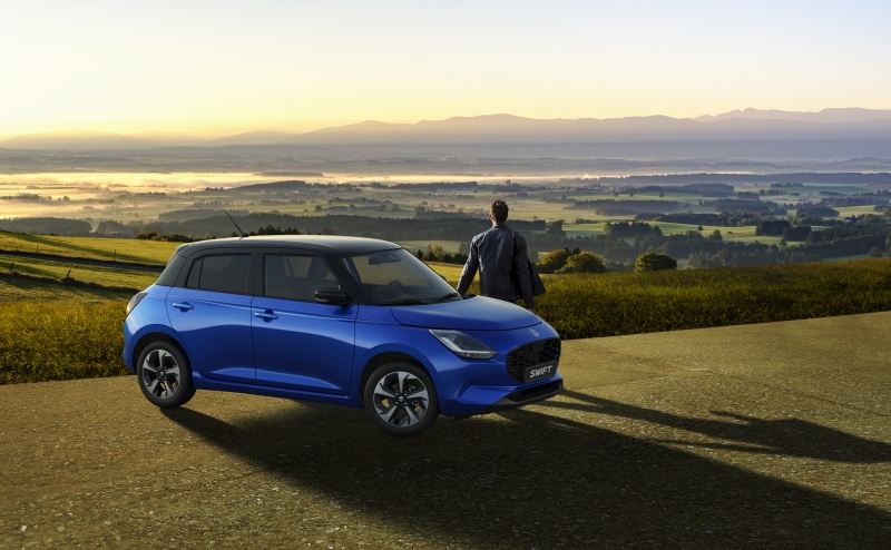 Nowy Suzuki Swift zaparkowany na tle panoramicznego widoku o zachodzie słońca