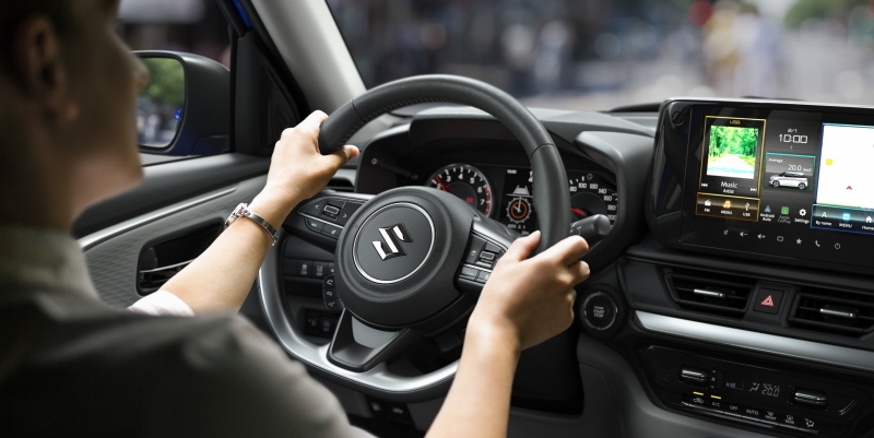 Kierowca trzymający kierownicę Suzuki Swift z widocznym ekranem multimedialnym