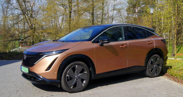 złoty nissan Ariya w parku bokiem/przodem, wynajem samochodu elektrycznego Nissana, promocja